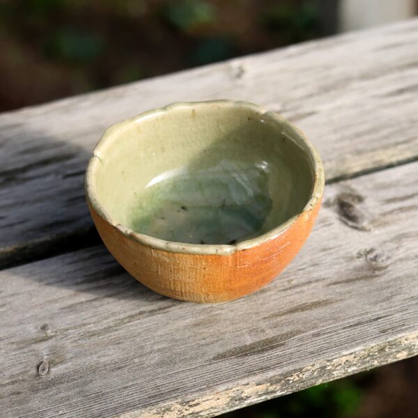 Le "Bol en grès - réf 61", au petit charme rustique avec son extérieur orange terreux et son intérieur vert, repose élégamment sur une surface en bois patiné, capturant l'essence de l'artisanat. - Atelier Terre et Bois à Colmar