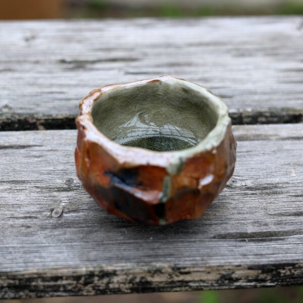 Une Coupelle en grès - kurinuki, fabriquée dans le style de poterie traditionnelle avec une texture rugueuse, repose sur une surface en bois patiné, mettant en valeur l'art exquis de l'artisanat. - Atelier Terre et Bois à Colmar